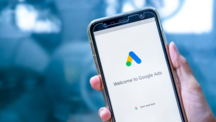 Hand holding phone with "welcome to Google Ads" on screen